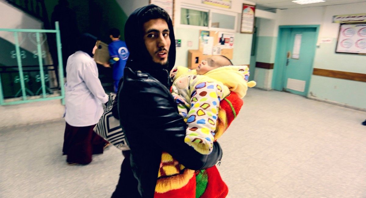 n hombre entra con su hijo a un hospital de Palestina